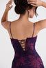 Woman wearing a purple floral dress with thin straps and lace-up back on a white background